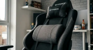 Close-up of the GT-FORCE gaming chair's upper back and headrest area, showing the adjustable lumbar support and neck cushions. The cushions are made from breathable grey fabric with high-quality stitching.