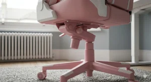 The sturdy five-star nylon base and smooth-rolling caster wheels of a pink desk chair on a wooden floor.