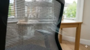 An extreme close-up photograph of the breathable grey mesh fabric on the backrest of the budget office chair, with diffused, natural British daylight highlighting its ventilation properties.