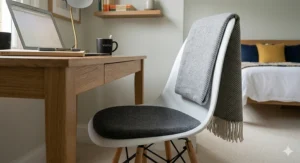 A comfortable grey upholstered guest room desk chair with a plush cushion placed in a cosy bedroom corner.