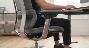 Professional working at a desk using an office chair with 4D armrests to maintain correct posture.