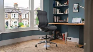 A sleek, armless extra tall drafting stool tucked neatly under a high workspace counter.