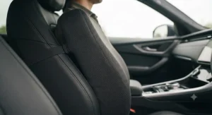 Driver using a memory foam lumbar support cushion fitted to a car seat for long journeys on the motorway.