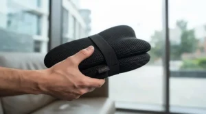 A portable mesh lumbar support cushion held by a commuter, highlighting its lightweight design for travel.