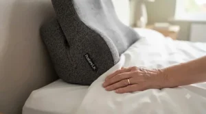 Supportive wedge cushion placed on a bed to help an elderly person sit up comfortably.